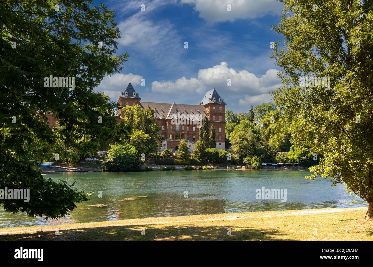 Turin, Piemont, Italien: Der Fluss Po mit dem Schloss Valentino (Castello del Valentino) zwischen den Bäumen im Park am Fluss und mit blauem Himmel und Stockfoto