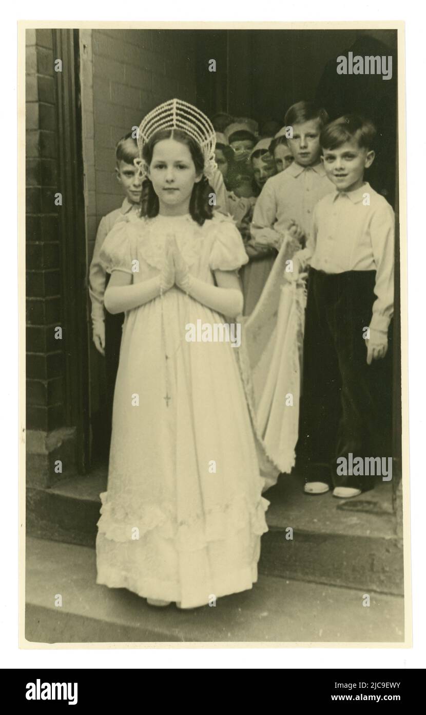 Originalpostkarte aus den 50er Jahren einer jungen May Queen vor der Kirche mit Anwesenden, katholischer Prozession, während das Mädchen einen Rosenkranz trägt, Großbritannien Stockfoto