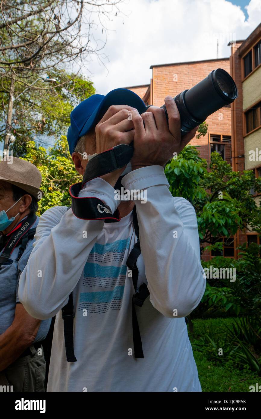 Medellin, Antioquia, Kolumbien - Februar 19 2020: Ein Erwachsener trägt eine blaue Kappe und macht in einem Garten Bilder von der Natur Stockfoto