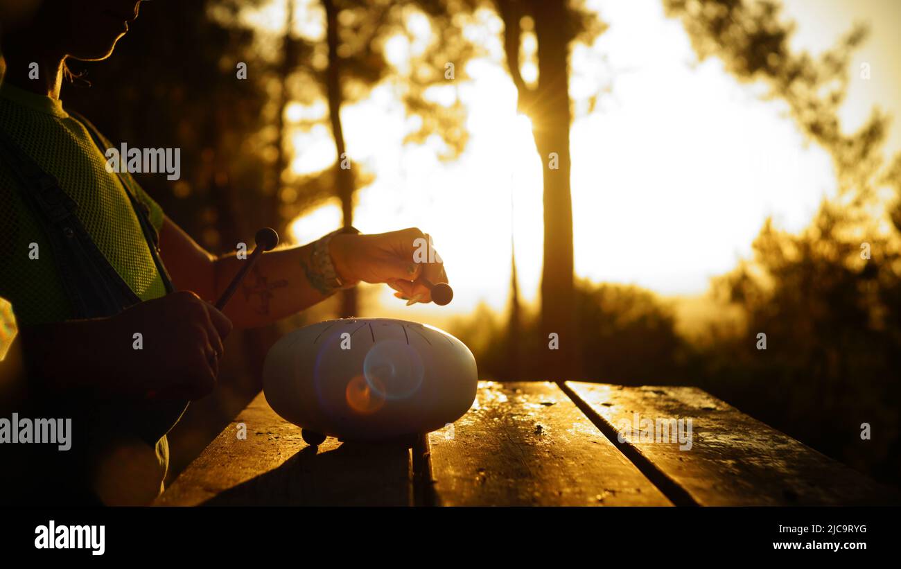 Frau spielt Stahlzungentrommel bei Sonnenuntergang Stockfoto