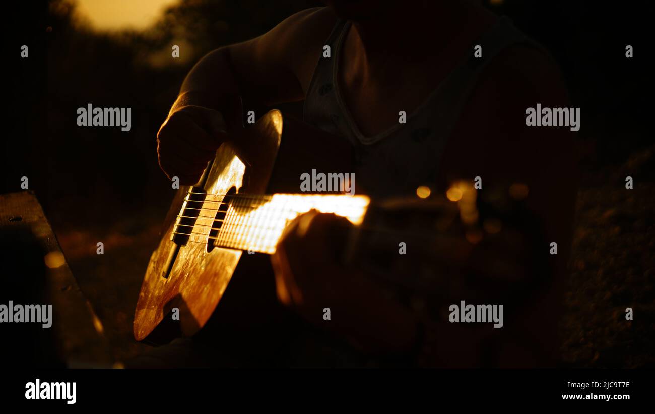 Mann spielt akustische Gitarre bei Sonnenuntergang Stockfoto