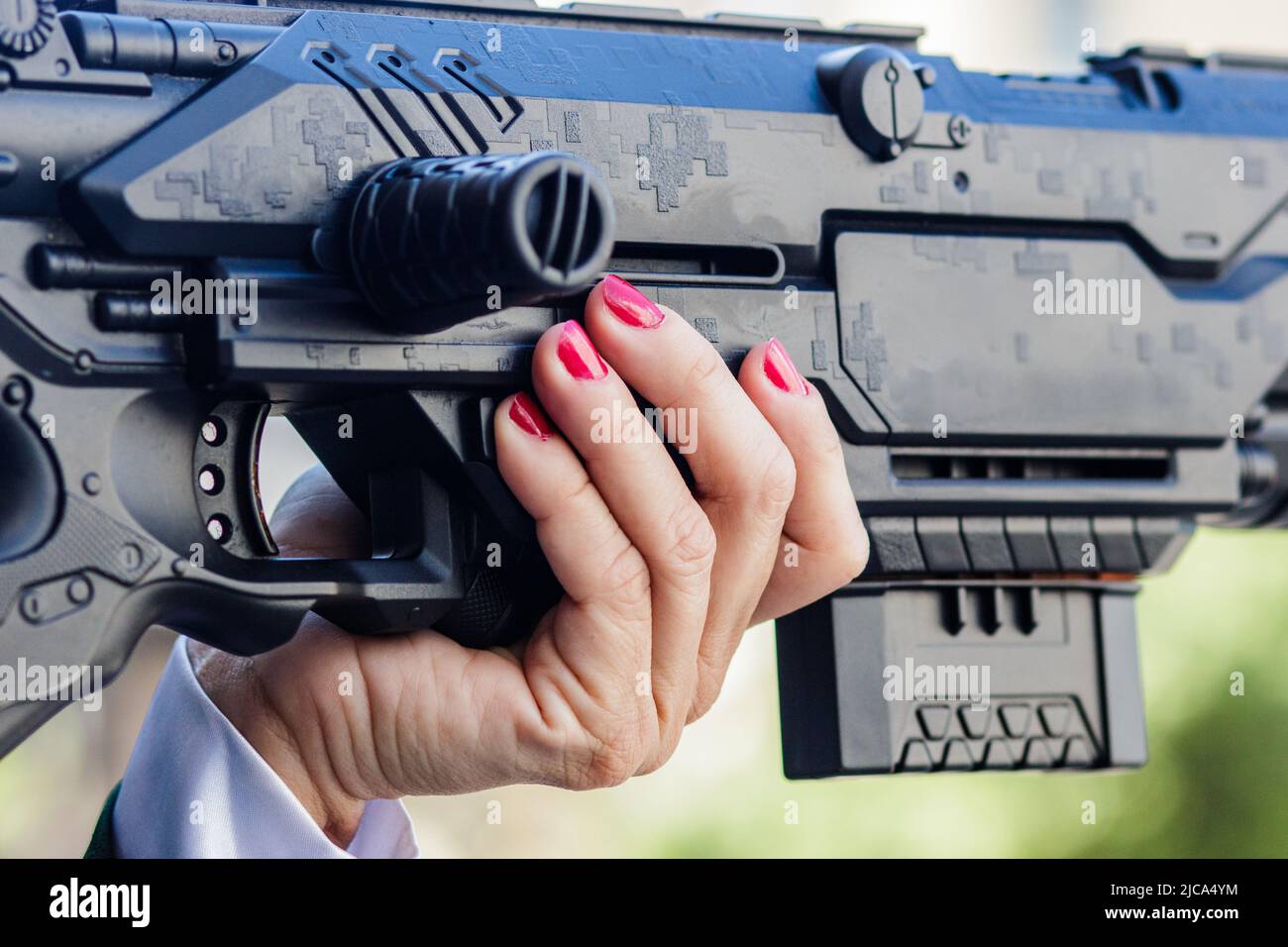 Frau mit roten Nägeln hält ein Spielzeuggewehr in Rio de Janeiro. Stockfoto