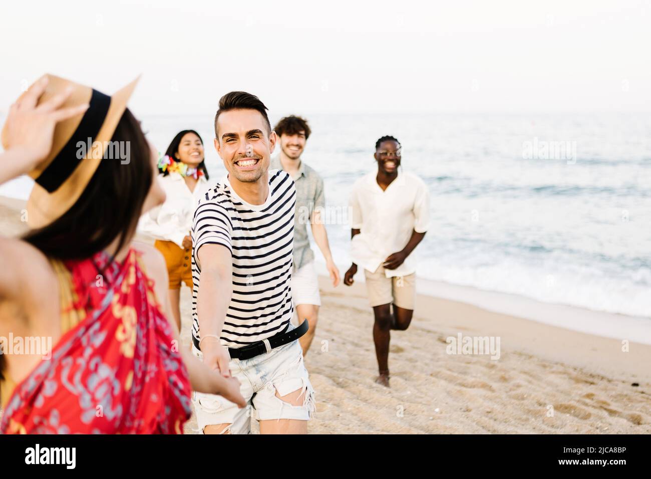 Eine Gruppe junger Freunde, die am Strand laufen Stockfoto