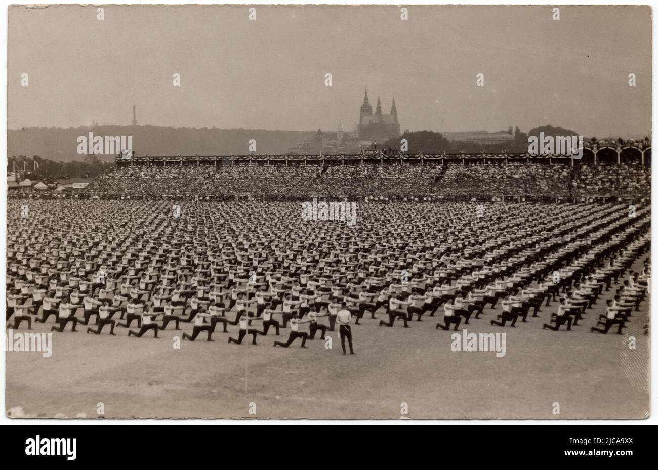 Sokol-Athleten treten im Juli 5. auf dem Letná-Plateau (Letenská pláň) in Prag, Österreich-Ungarn, auf dem Sokol-Massenturnfestival (V. všesokolský slet) im Juli 1907 auf. Schwarz-Weiß-Vintage-Fotografie eines unbekannten Fotografen, veröffentlicht auf der Vintage-Postkarte, die anlässlich des Sokol-Massenturnfestivals 5. ausgestellt wurde. Im Hintergrund ist die St.-Veits-Kathedrale auf der Prager Burg zu sehen. Mit freundlicher Genehmigung der Azoor Postkartensammlung. Stockfoto