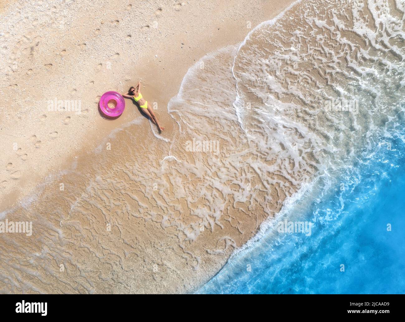 Luftaufnahme einer jungen Frau mit rosa Schwimmring am Sandstrand Stockfoto