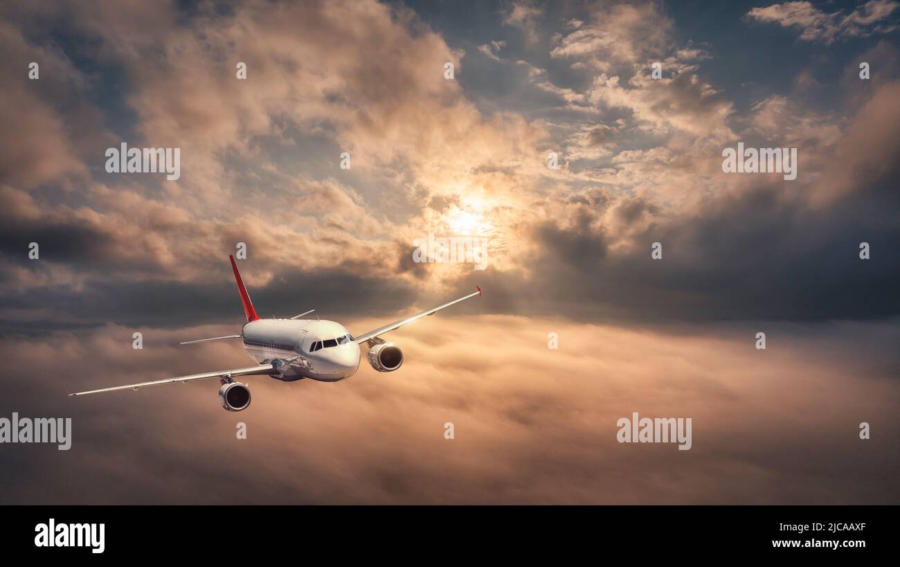 Das Flugzeug fliegt im Sommer bei Sonnenuntergang über den Wolken Stockfoto