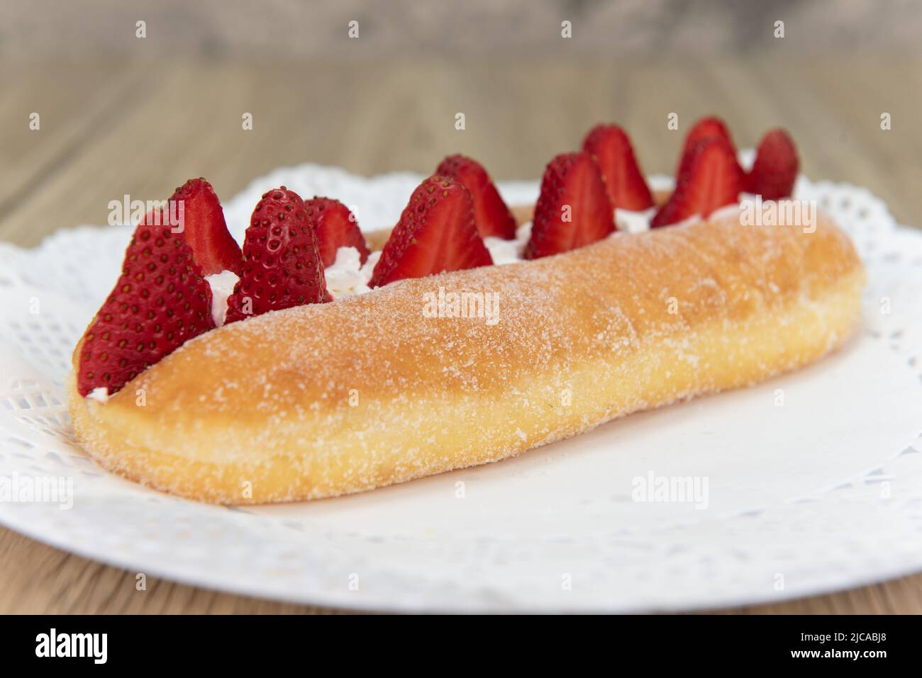 Verführerisch frisch aus dem Ofen frischer Erdbeer-Suguar-Donut aus der Bäckerei auf einem Teller serviert. Stockfoto