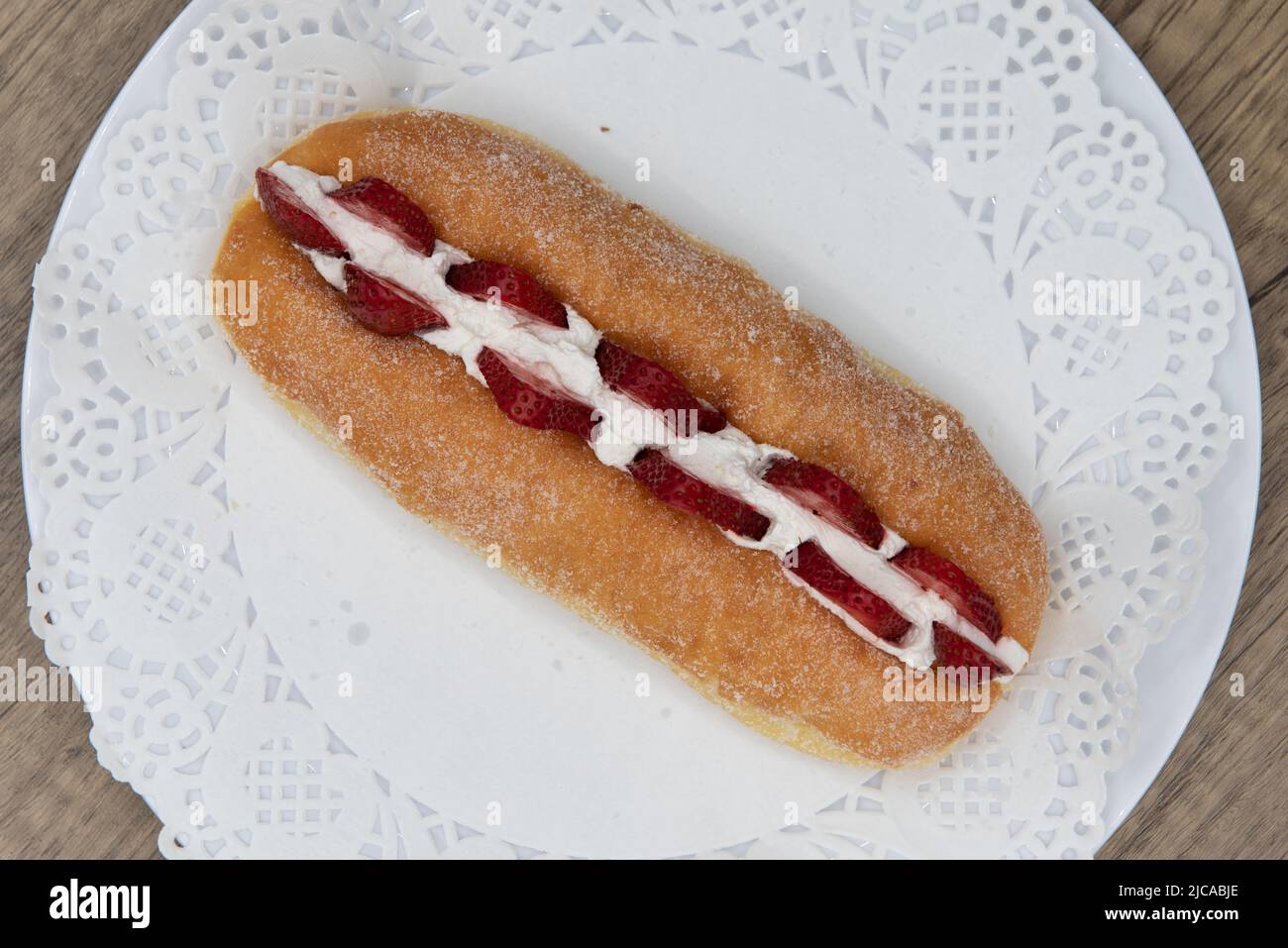 Blick von oben auf verführerisch frisch aus dem Ofen frischer Erdbeer-Suguar-Donut aus der Bäckerei auf einem Teller serviert. Stockfoto