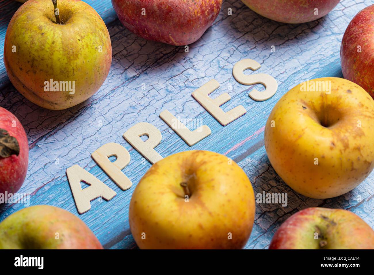 Viele gelbe und rote Äpfel Obst mit Äpfeln Wort auf Holzbuchstaben auf blauem Hintergrund geschrieben Stockfoto