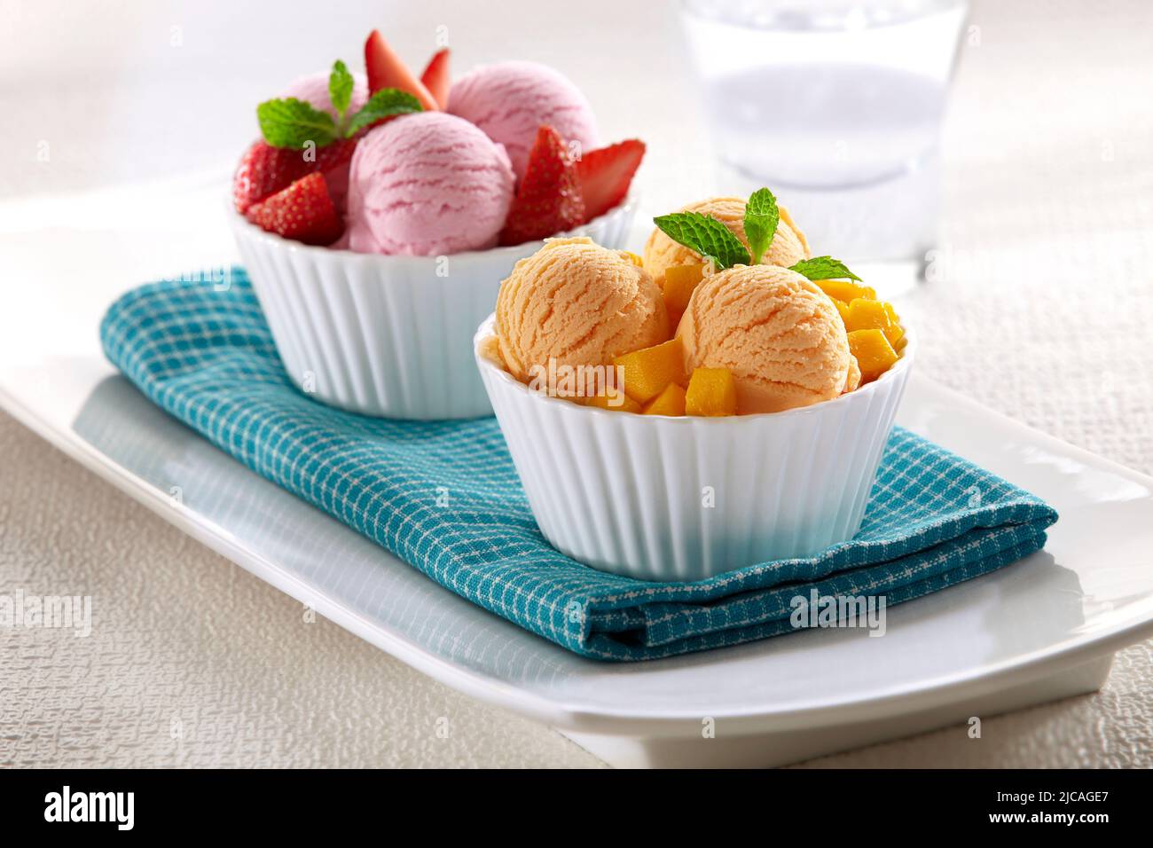 Zwei Schalen Eis mit Erdbeer- und Mango-Aromen, serviert mit Fruchtstücken nach ihrem Geschmack Stockfoto