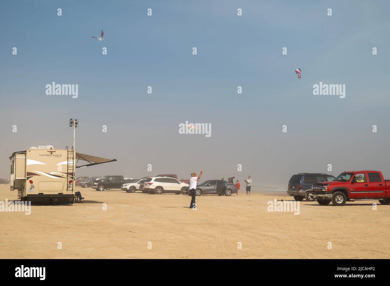 PORT ARANAS, TX - 16. FEB 2020: Autos und andere Fahrzeuge und Menschen, die an einem windigen Tag Drachen an einem verschwommenen und sandigen Strand fliegen. Stockfoto