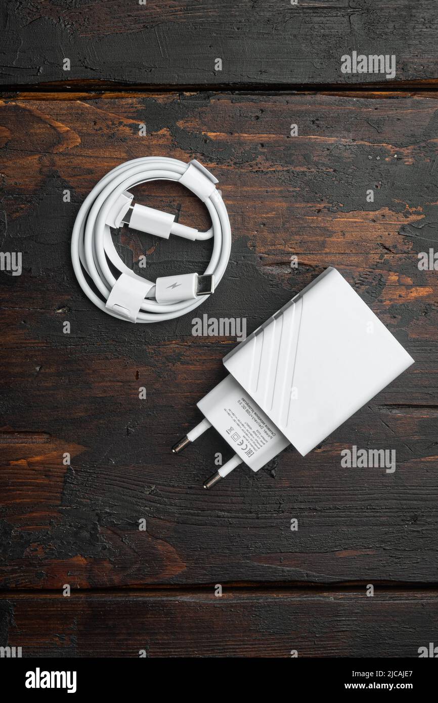 Zubehör für ein Smartphone, Ladegerät, auf altem dunklem Holztischhintergrund, Draufsicht flach liegend Stockfoto