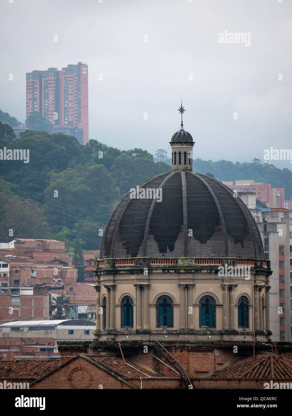 Blick auf die Kathedrale und die Gebäude in der Stadt Medellin, umgeben von grünen Bergen an einem bewölkten Tag Stockfoto