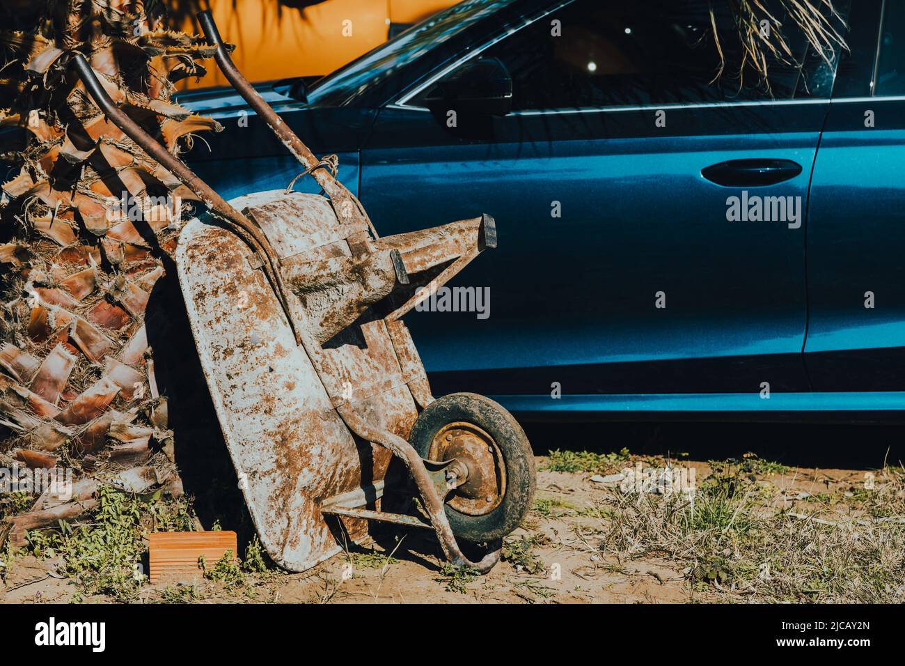 Eine Schubkarre und ein Luxusauto stehen nebeneinander. Automobilgeschichte Stockfoto