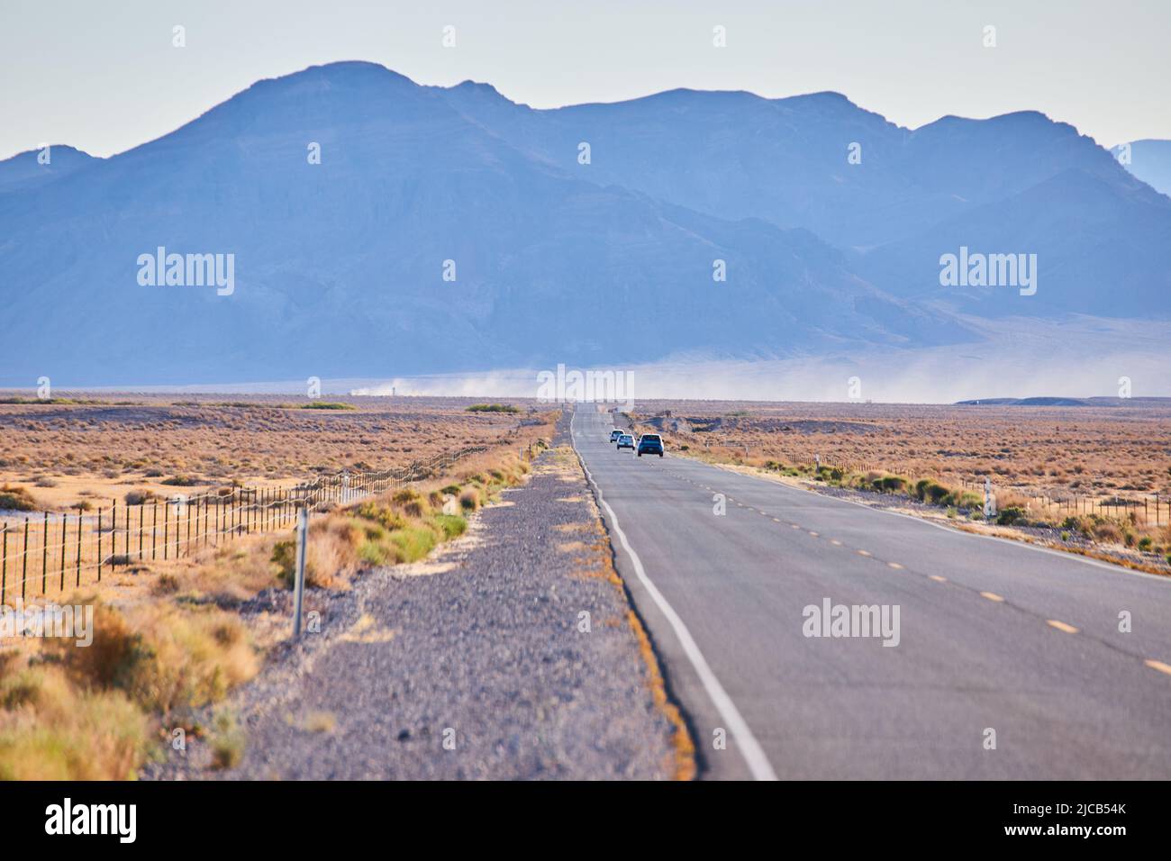 Große Berge im Hintergrund als Autobahn führt durch Wüstenebenen Stockfoto