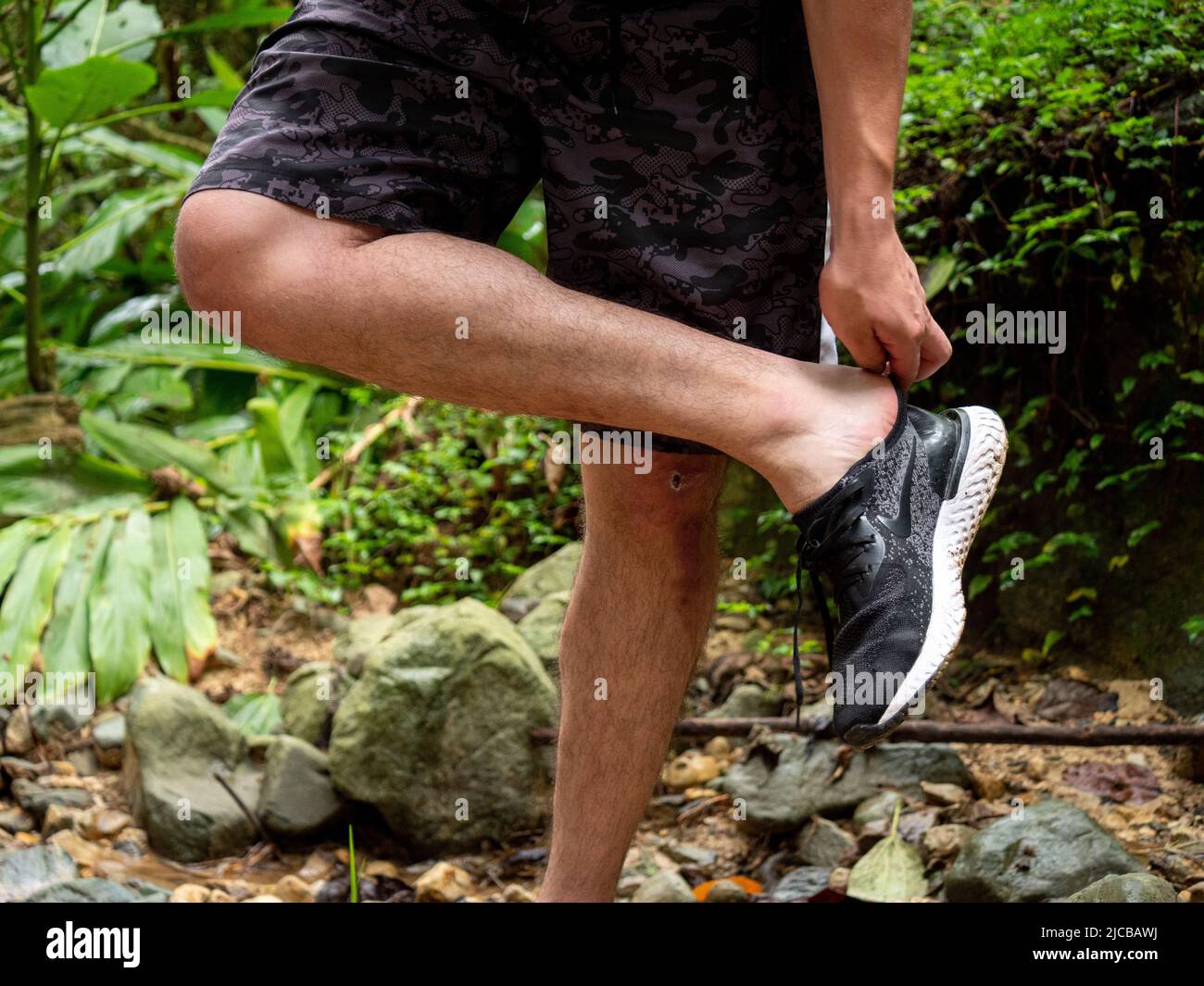La Estrella, Antioquia, Kolumbien - 13 2022. Februar: Der Mann zieht seine Schuhe aus der schmutzigen Straße des Waldes Stockfoto