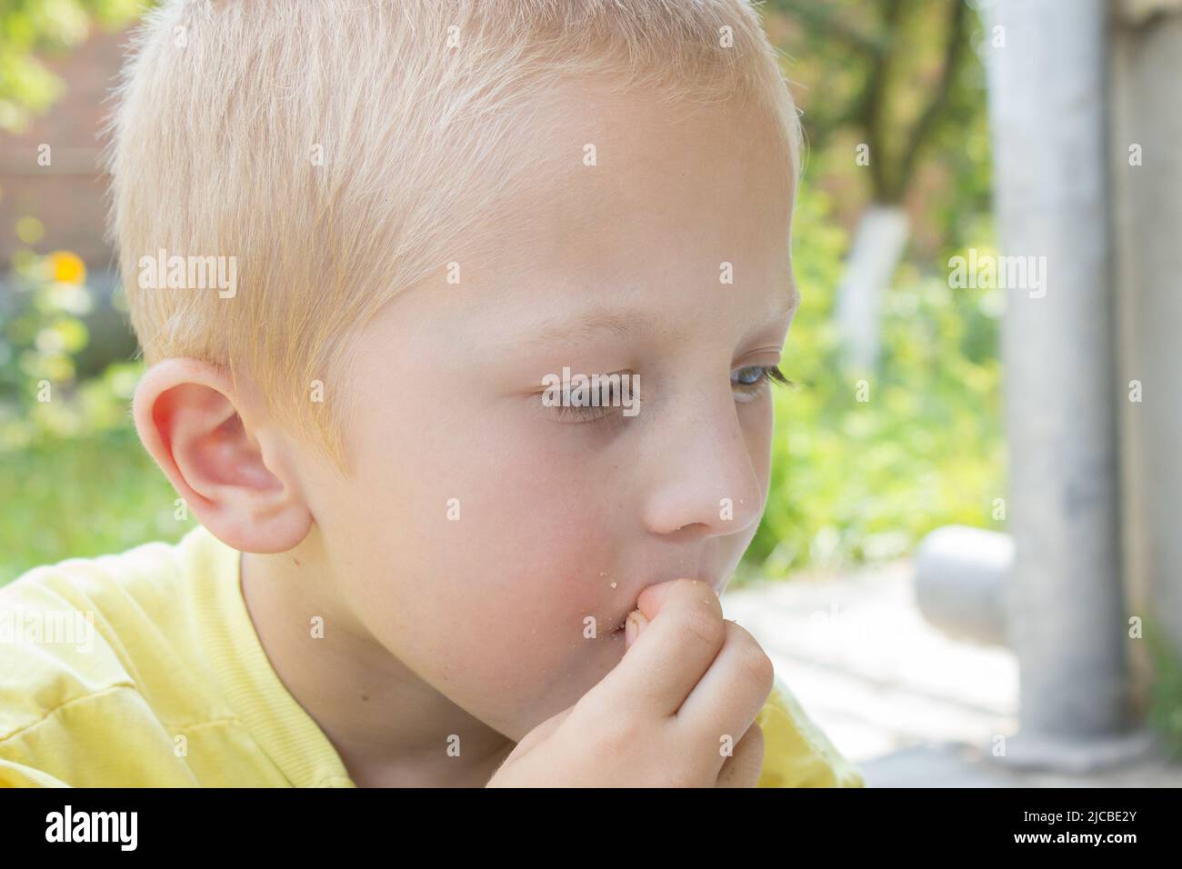 Portrait blonder Junge, der mit seinen Händen isst Stockfoto