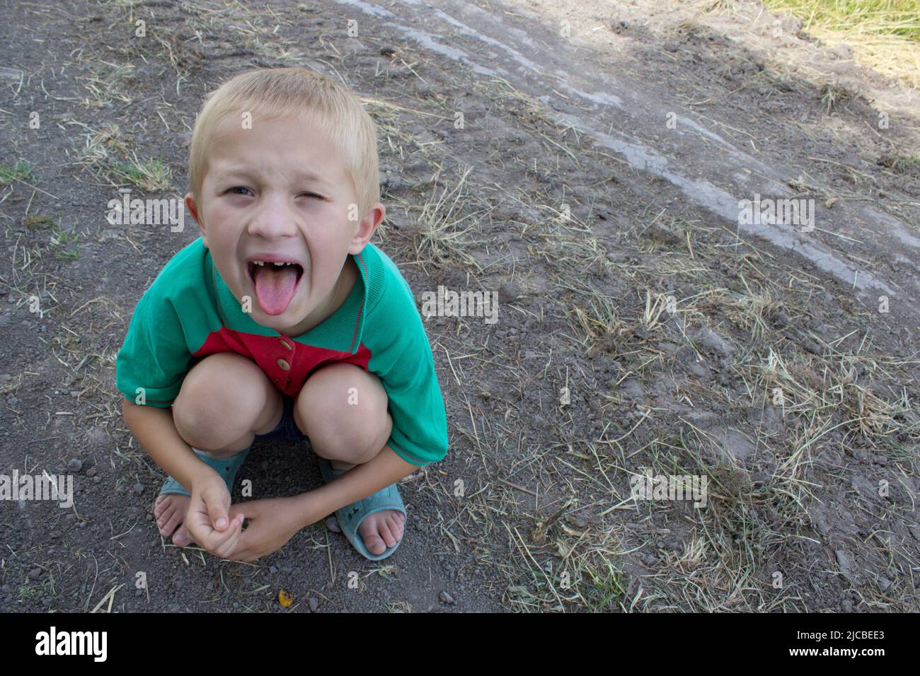 Boy zeigt Zunge auf dem Boden sitzen Stockfoto