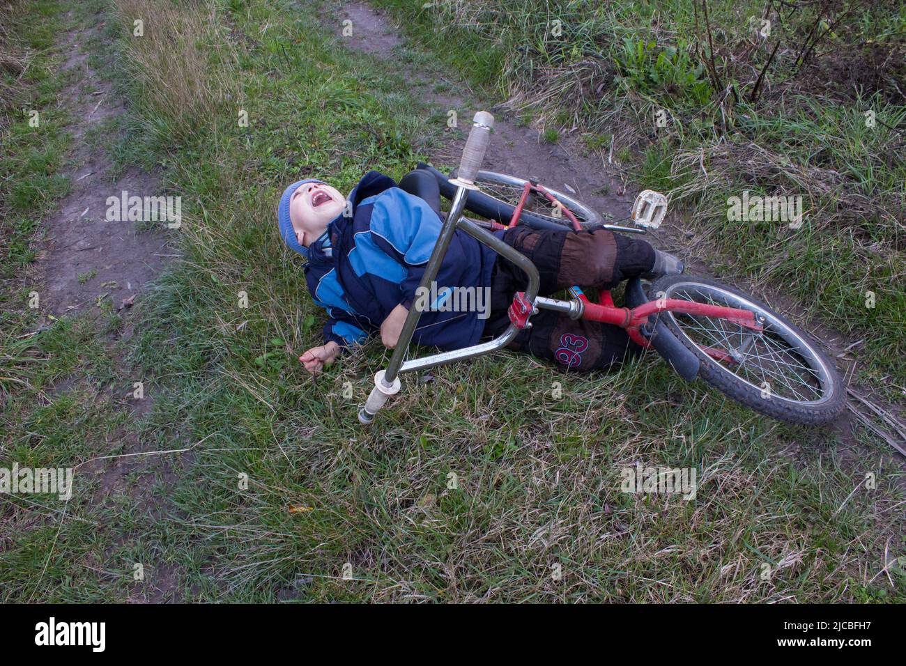 Boy fiel vom Fahrrad auf der Straße in einem Feld Stockfoto