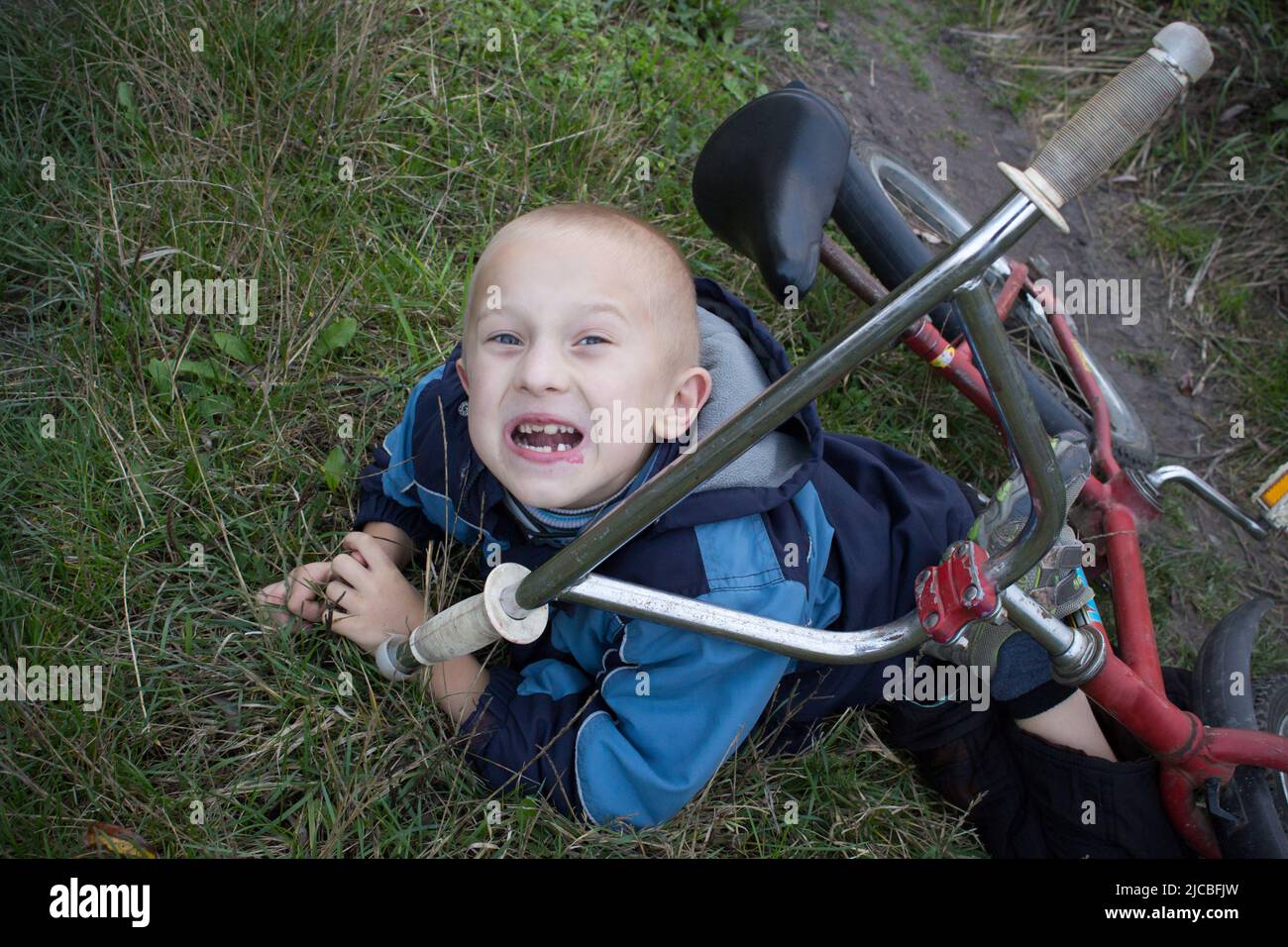 Junge in der Straße Boden mit einer Knieverletzung schreien nach Herausfallen der sein Fahrrad Stockfoto