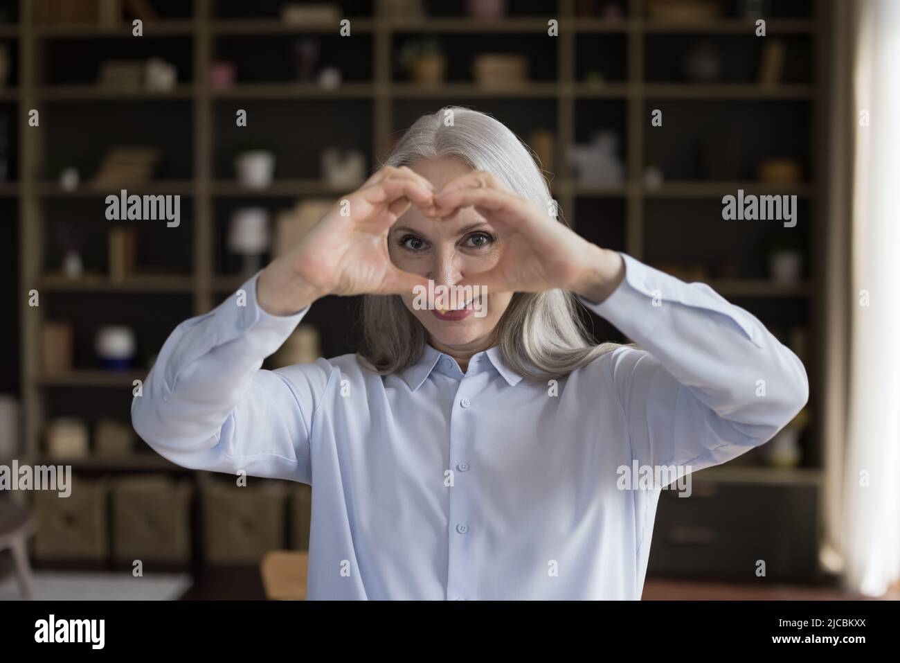 Glückliche Frau mittleren Alters verbinden sich die Finger zeigen Symbol der Liebe Stockfoto
