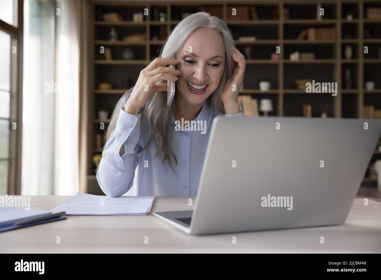 Attraktive ältere Geschäftsfrau, die im Büro arbeitet, genießt Geschäftsanruf Stockfoto