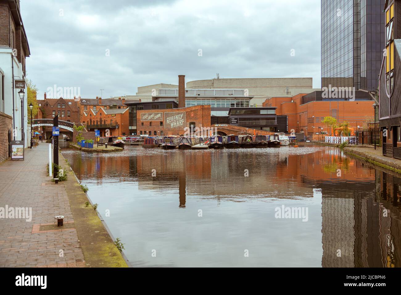 Hausboote Reihen sich auf dem Kanal am Regency Wharf an, umgeben von der Gegenüberstellung alter und neuer Architekturstile. Stockfoto