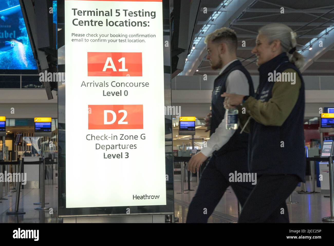 Die Passagiere gehen in Richtung der Beschilderung zum Covid-Testzentrum am Flughafen London Heathrow, England, Großbritannien Stockfoto
