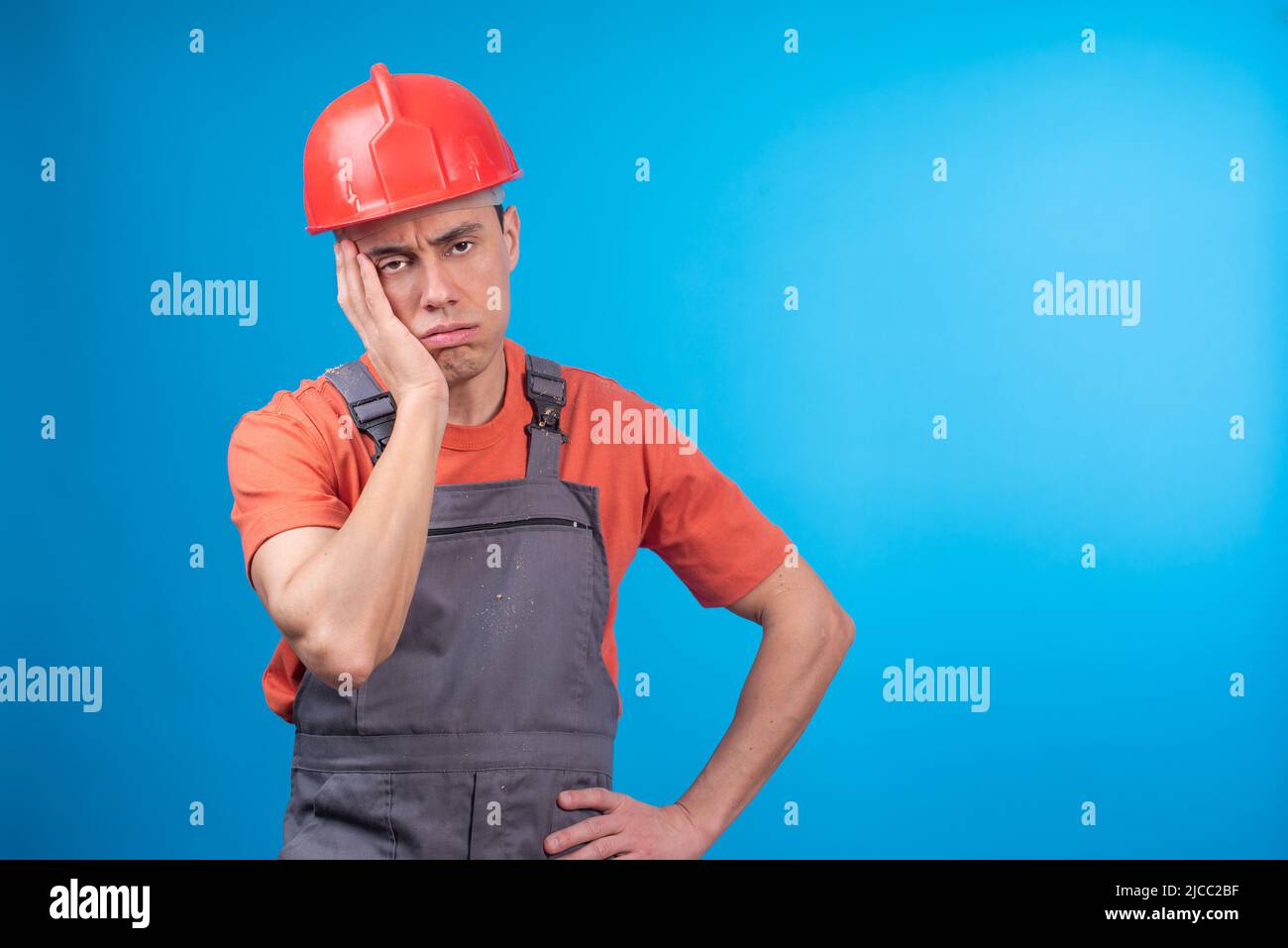 Müde männliche Auftragnehmer in Uniform berühren Gesicht Stockfoto