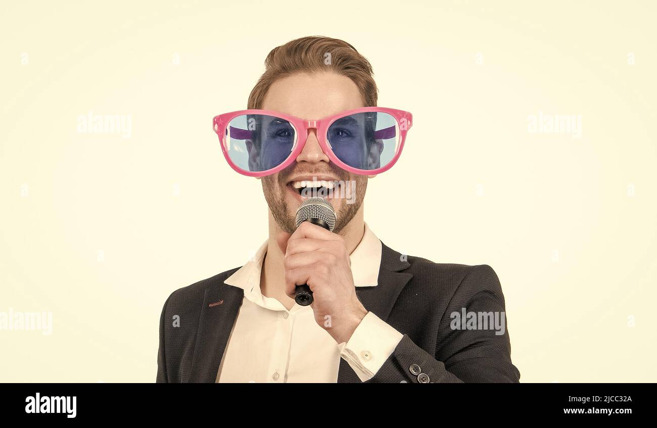 Porträt eines glücklichen Mannes in formalwear und lustige Brillen singen Lied an Mikrofon, singen Stockfoto