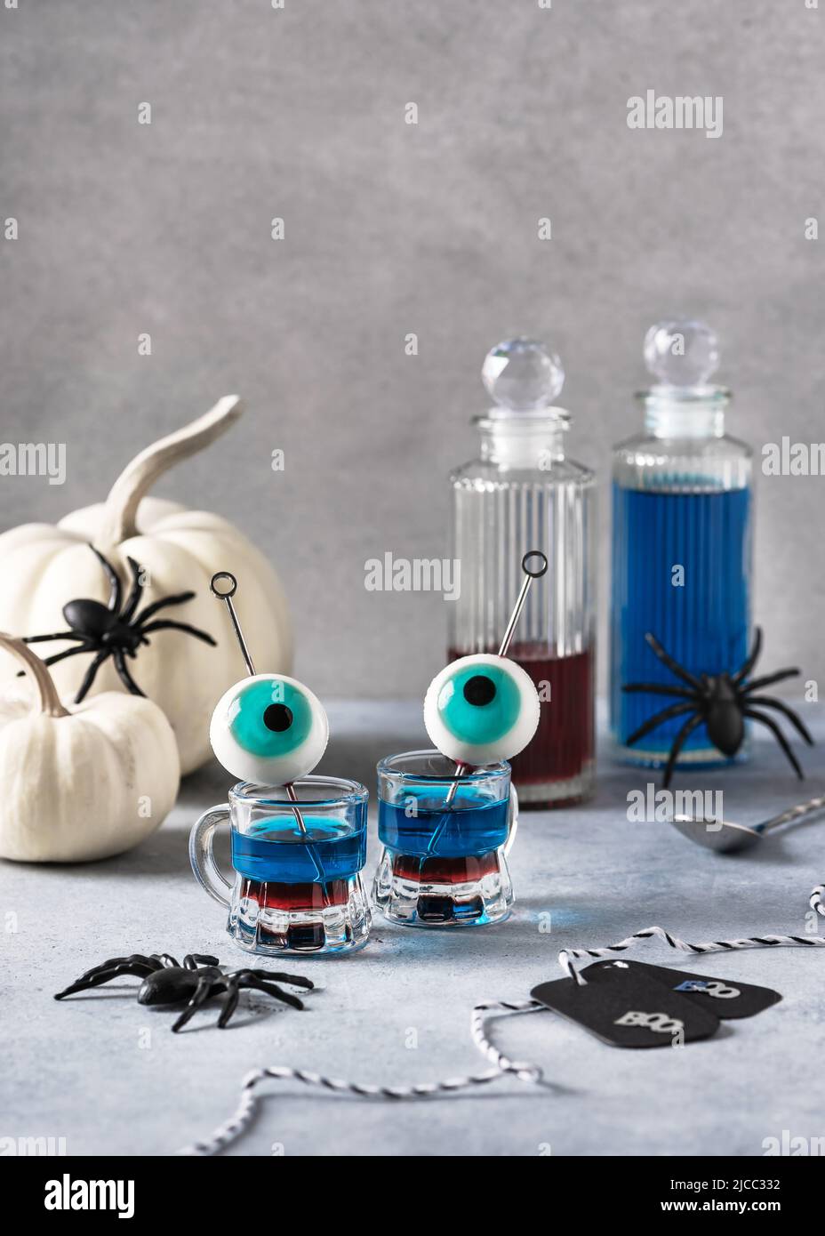 Geschichtetes Getränk, zubereitet mit Wodka, blauem Alkohol, Himbeersirup und dekoriert mit türkisfarbenen Gelee-Augäpfeln. Stockfoto