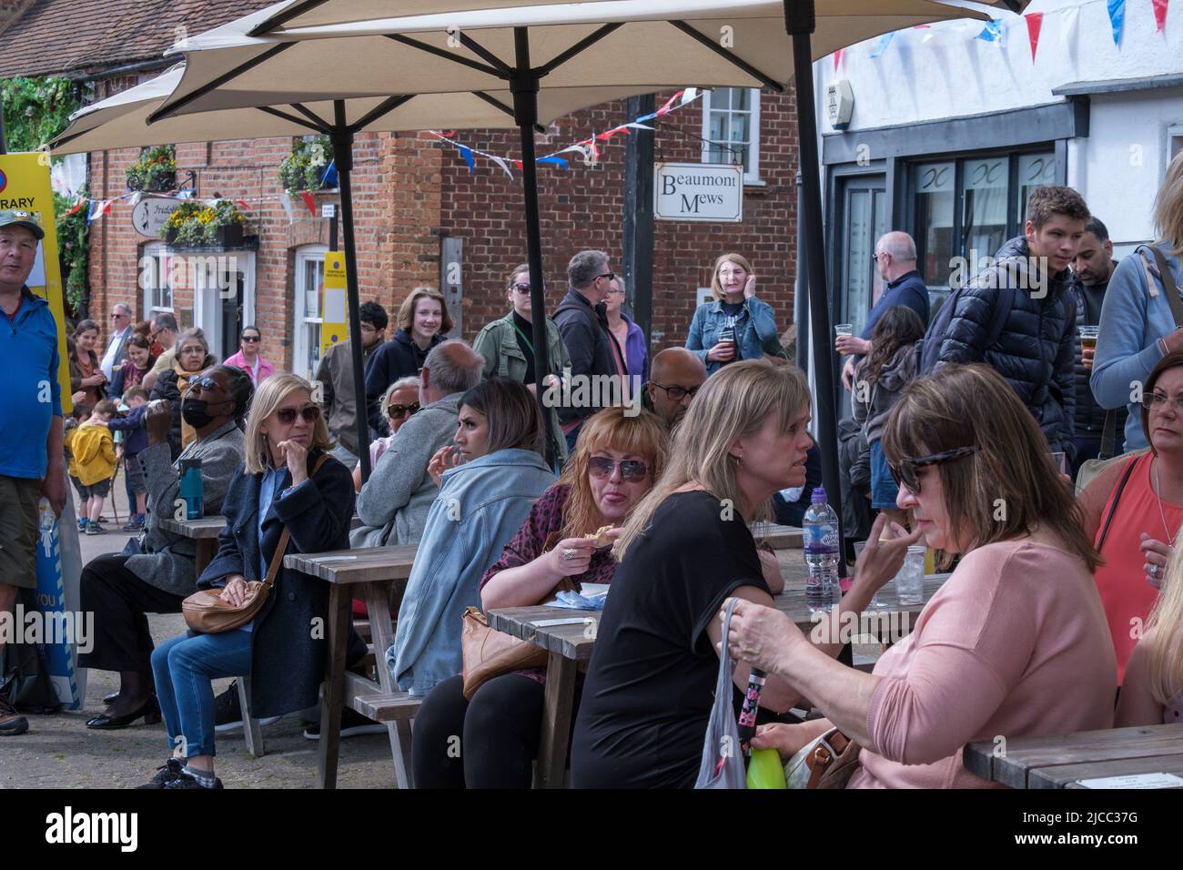 Während der St. George’s Day-feiern 2022 sitzen und trinken die Leute an Tischen und stehen vor dem Queens Head Pub in Pinner, Northwest London. Stockfoto