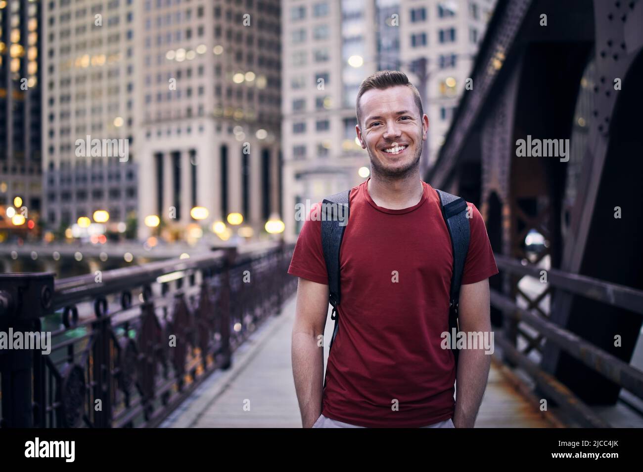 Vorderansicht eines lächelnden Mannes, der auf die Kamera auf der abendlichen Stadtstraße schaute. Stockfoto