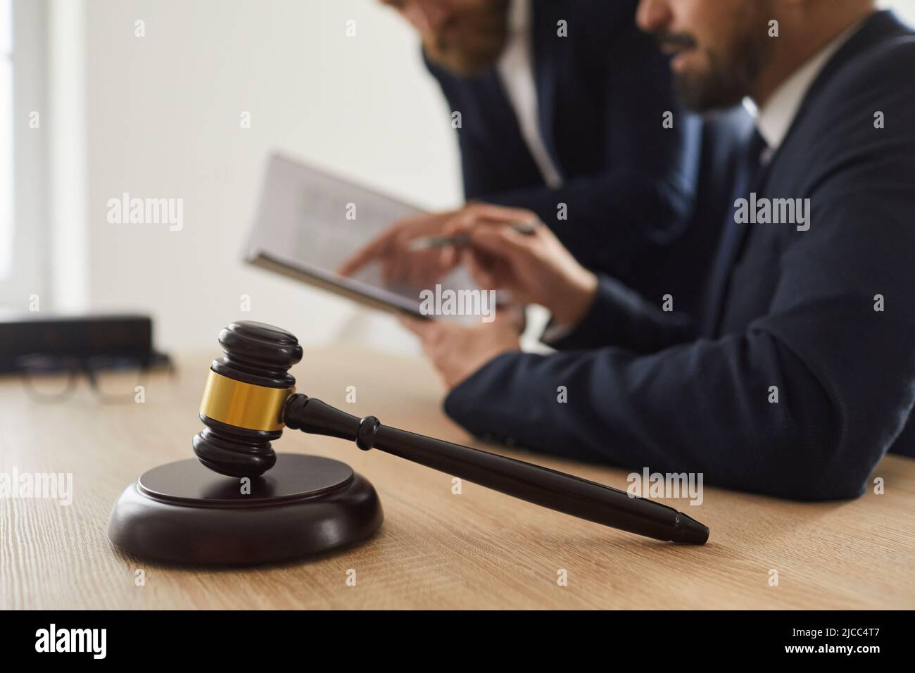 Nahaufnahme des Richters Gavel, der auf einem Schallblock auf dem Tisch vor dem Hintergrund des Richters und des Anwalts steht. Stockfoto