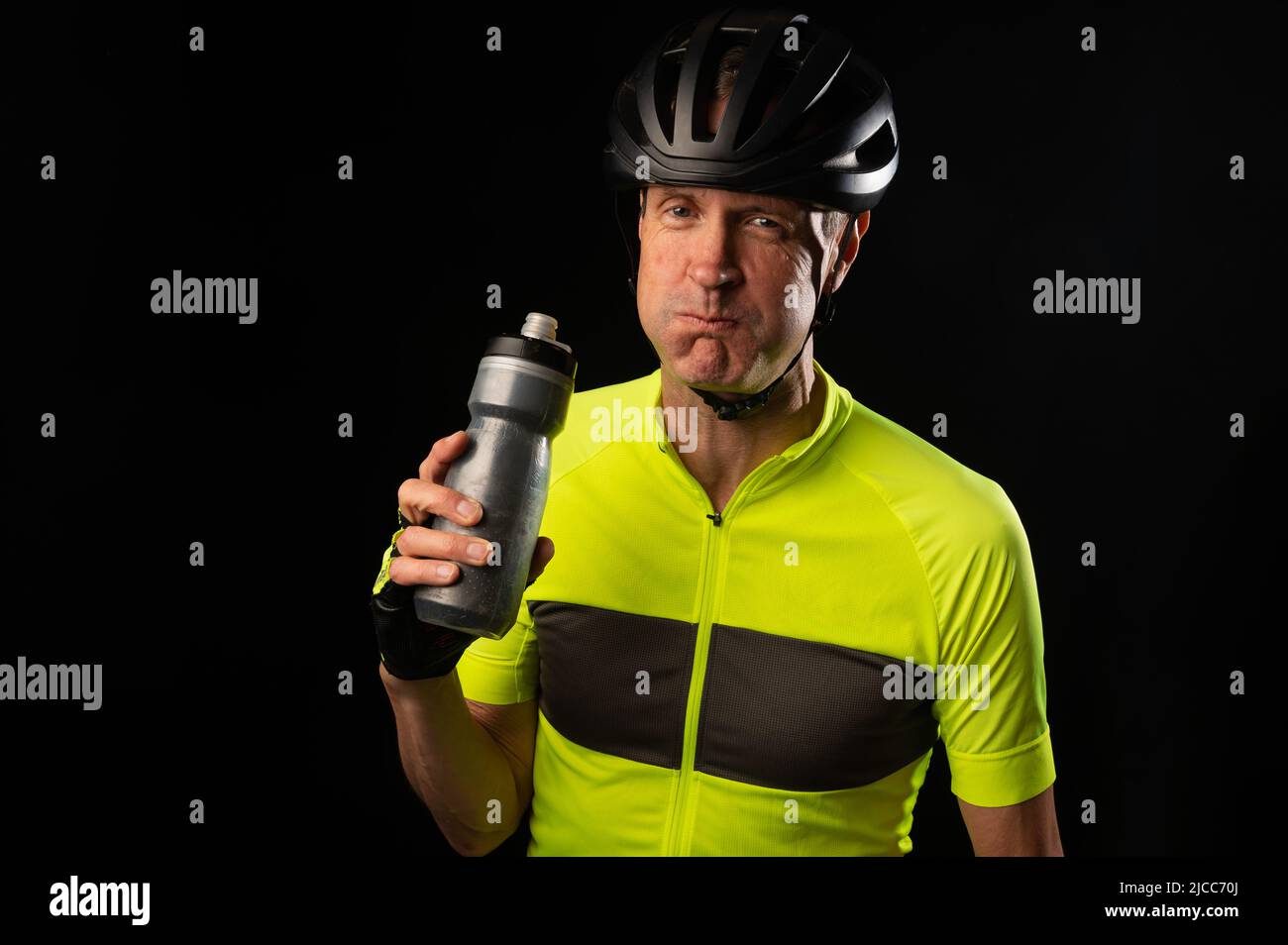 Radfahrer trinken aus einer Wasserflasche auf schwarzem Hintergrund mit Kopierplatz Stockfoto