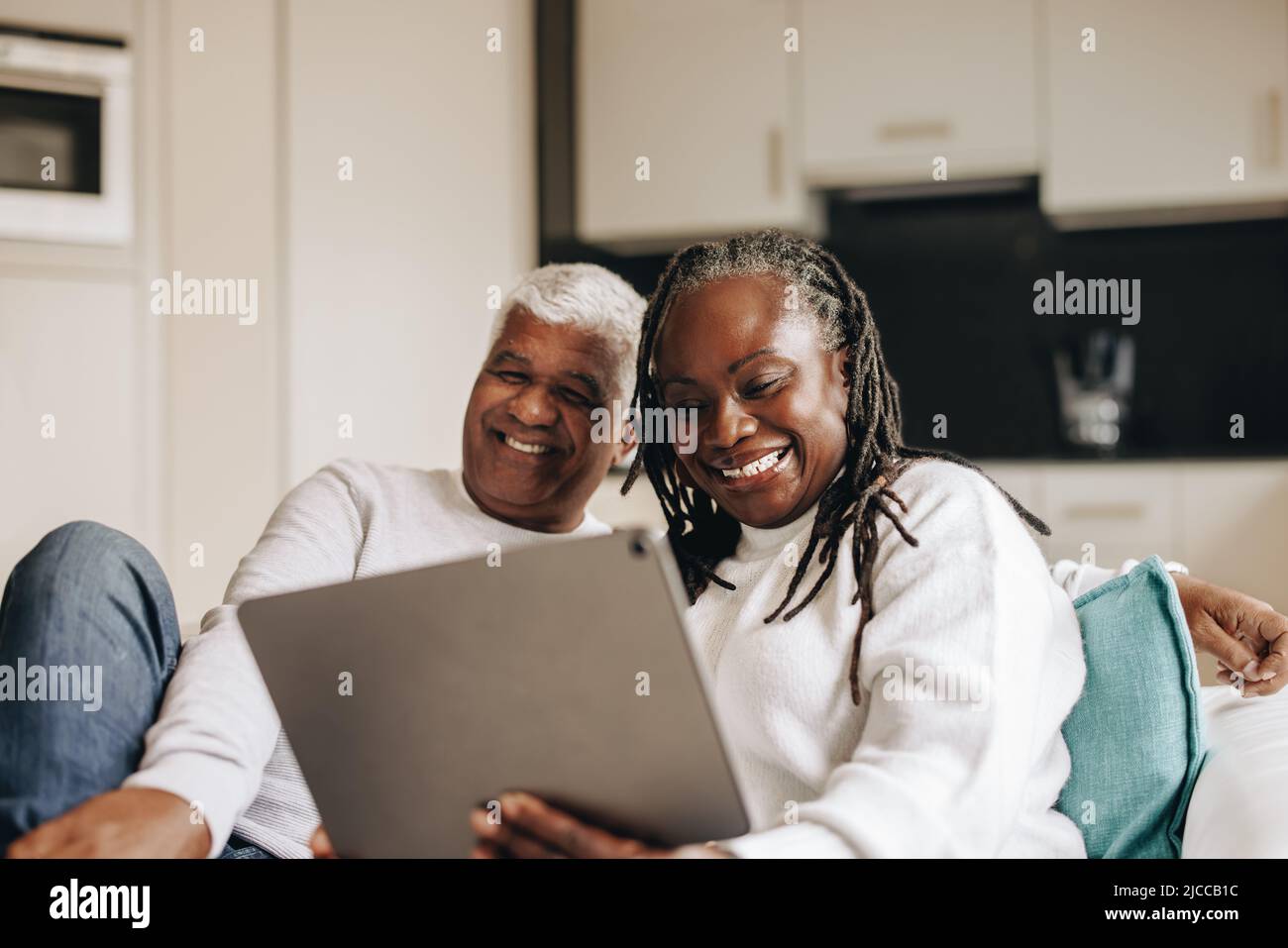 Sorgloses Seniorenpaar, das fröhlich lächelt, während er einen Videoanruf auf einem digitalen Tablet hat. Ältere Paare kommunizieren online mit ihren Angehörigen. Reif Stockfoto