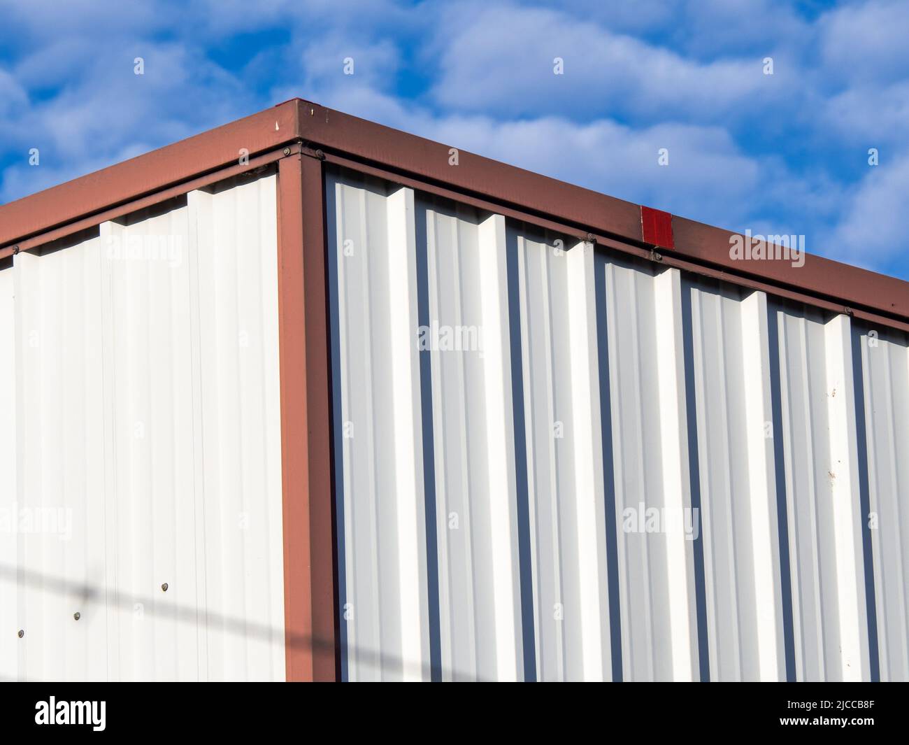 Lagerhaus in weiß-roter Stahlkonstruktion unter blauem Himmel Stockfoto