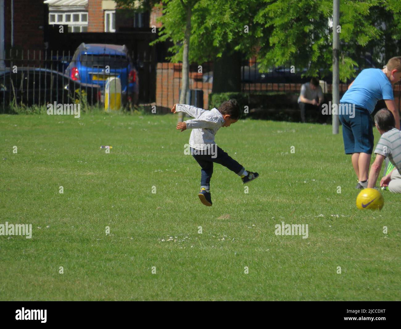 Ein kleiner Junge, der an einem heißen, sonnigen Tag mitten in der Luft im Park springt Stockfoto