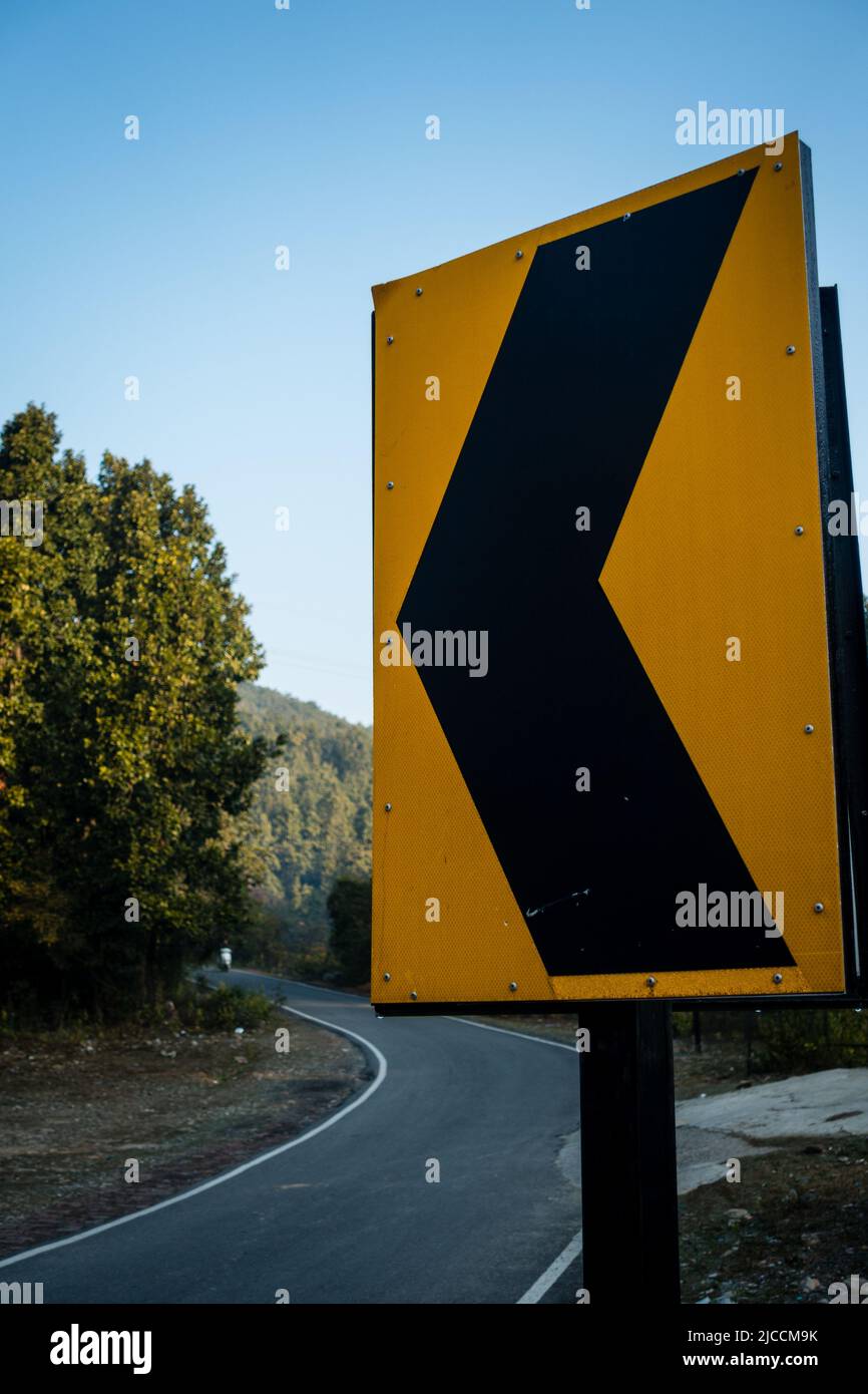 Ein Schild mit einem Pfeil nach links an einer Straße im Waldgebiet der Stadt dehradun. Uttarakhand Indien Stockfoto