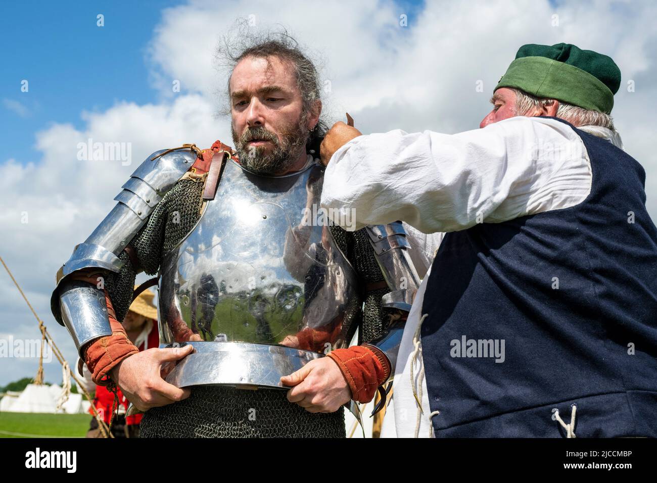 London, Großbritannien. 12. Juni 2022. (L) James Simmonds, ein Re-enactor, wird während des Barnett Medieval Festivals im Norden Londons als Mann an den Armen der De Cobhams (Yorkisten) für den Kampf vorbereitet. Es ist das einzige mittelalterliche Fest der Hauptstadt und widmet sich der Auseinandersetzung mit der Geschichte der Schlacht von Barnett und ihrer Bedeutung im Rahmen der Rosenkriege. In der Schlacht von Barnett führte Edward IV. Seine Yorkistische Armee am 14.. April 1471 zum Sieg gegen die Lancastrian-Truppen unter der Führung des Earl of Warwick. Kredit: Stephen Chung / Alamy Live Nachrichten Stockfoto