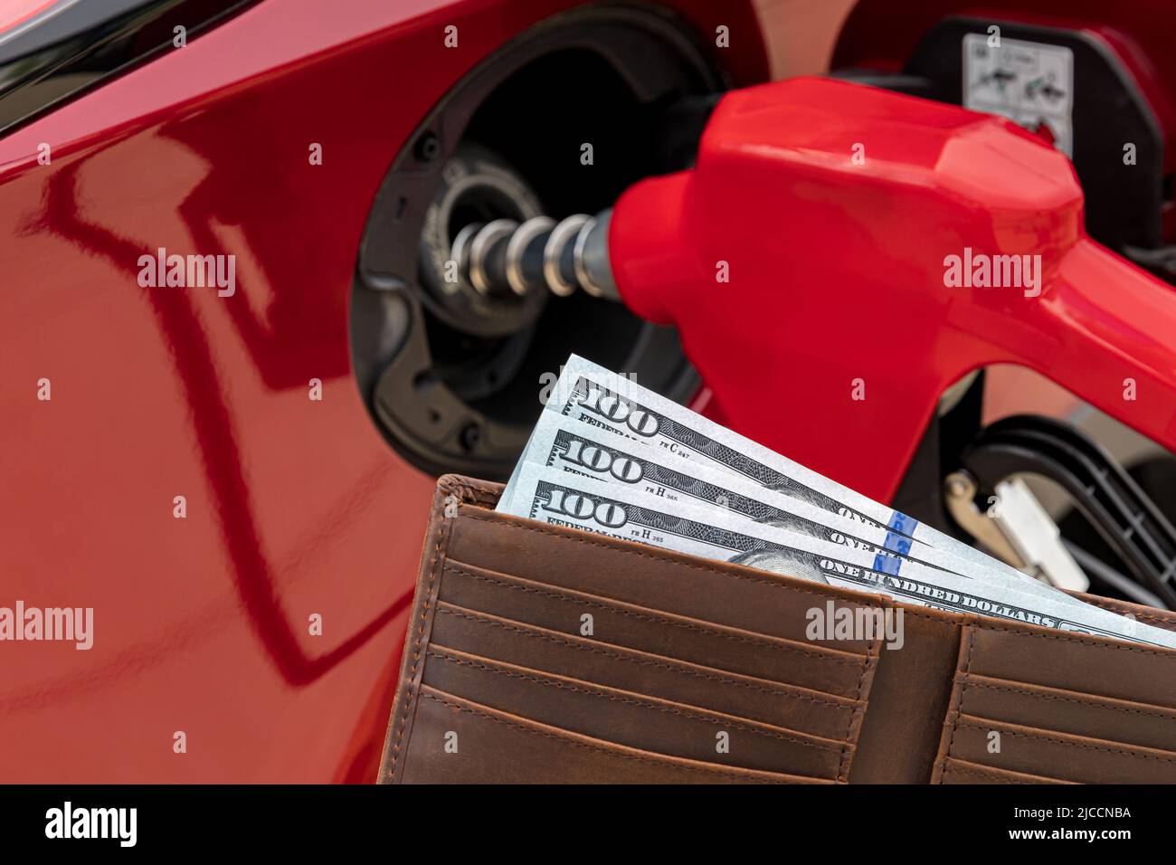 Das Auto wird an der Tankstelle mit Bargeld in der Brieftasche betankt. Konzept für die Erhöhung der Gaspreise, Steuern und Kraftstoffknappheit. Stockfoto