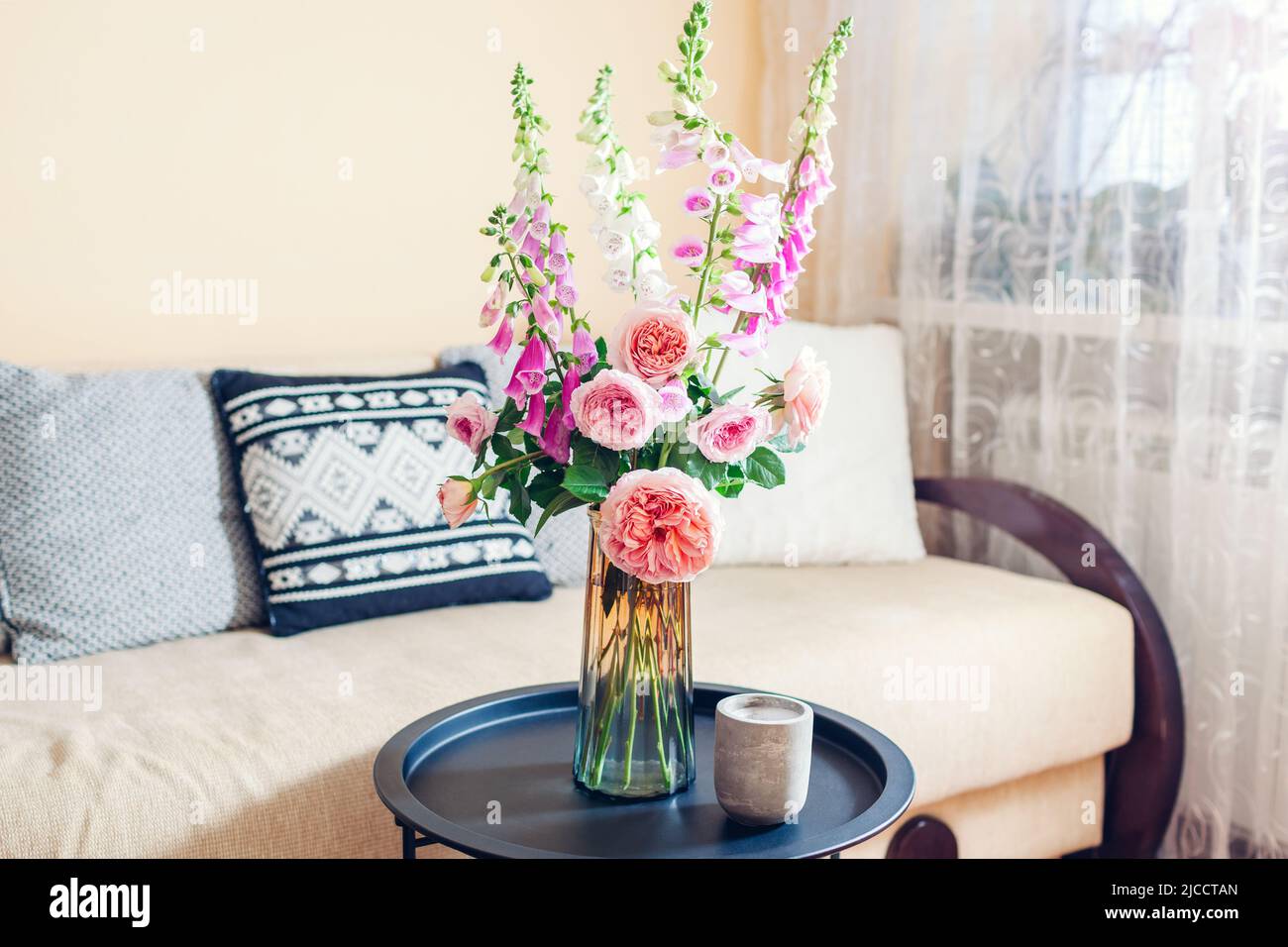 Frischer Strauß von Rosen und Füchshandschuhen Blumen in Vase im Wohnzimmer gelegt. Inneneinrichtung und Inneneinrichtung. Rosa orange blüht auf dem Tisch Stockfoto