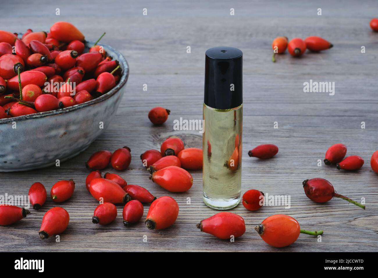 Hunderose (Rosa Canina), roter Hagebuttenöl-Extrakt und natürliche rote Früchte auf einer Schüssel Stockfoto