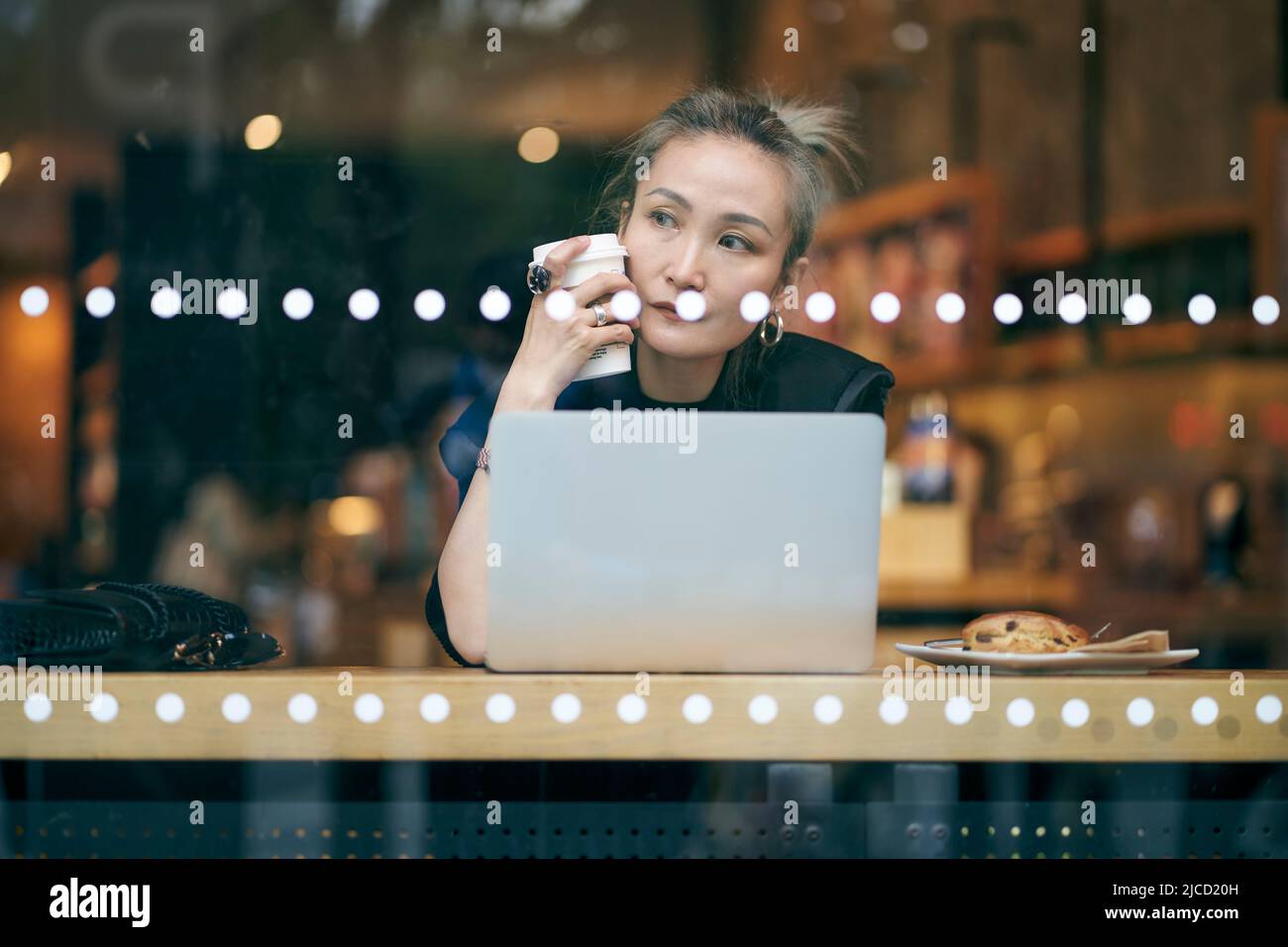 Mittelgroße asiatische Geschäftsfrau, die im Café mit einem Laptop arbeitet Stockfoto