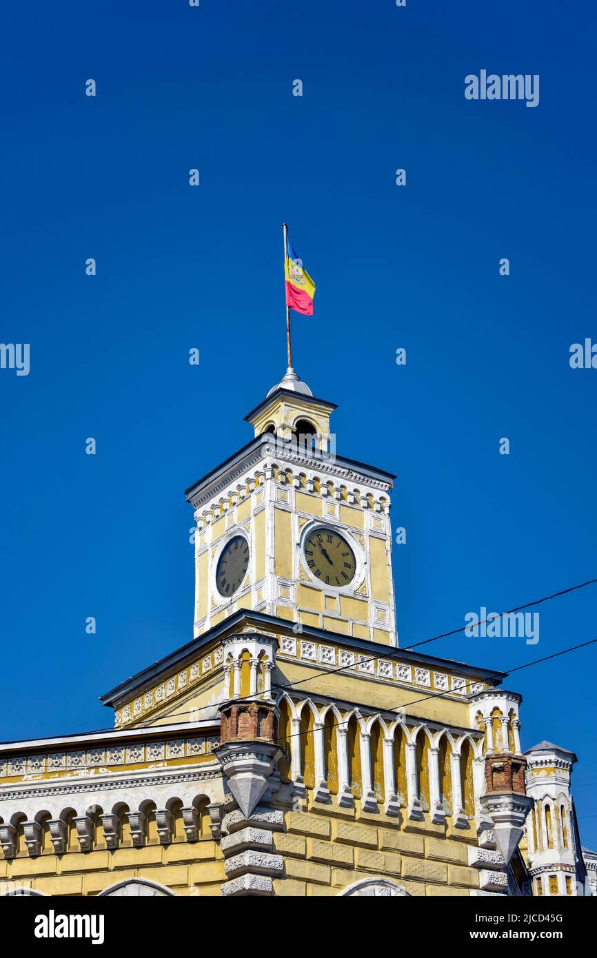 Die moldauische Flagge ist auf dem Uhrenturm des alten Gemeindegebäudes befestigt. Moldauische Flagge auf blauem Himmel Hintergrund. Chisinau, Moldawien - Juni 2022 Stockfoto