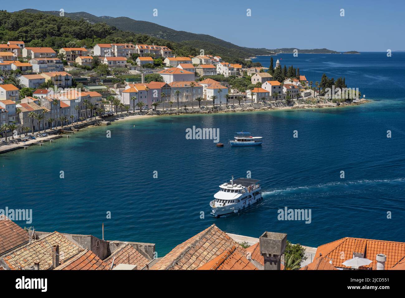 Ausflugsboot nähert sich West Harbour, Korcula Island, mit Häusern der Neustadt im Hintergrund Stockfoto
