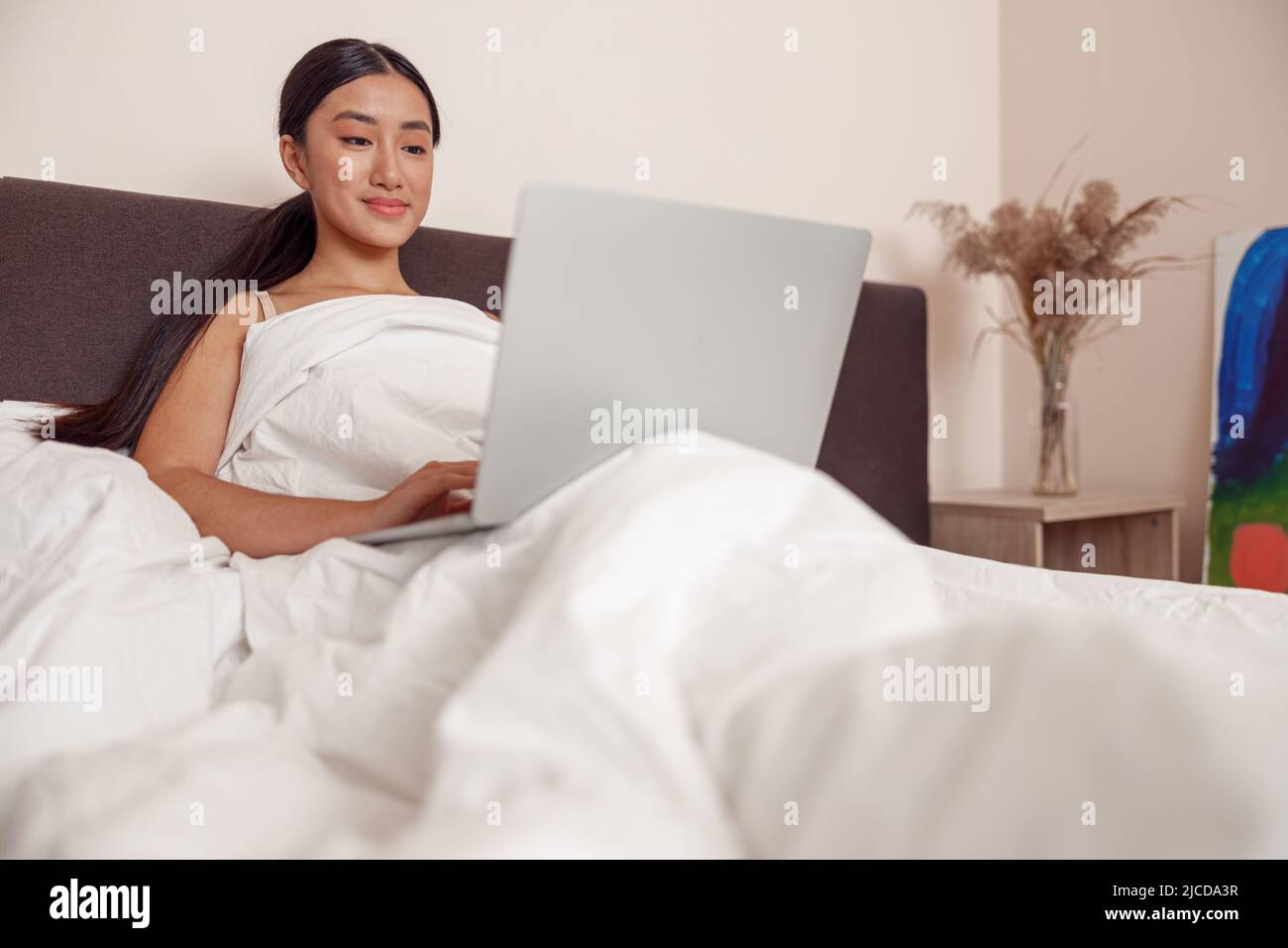 Asiatische junge Frau mit modernen Laptop zu Hause Stockfoto