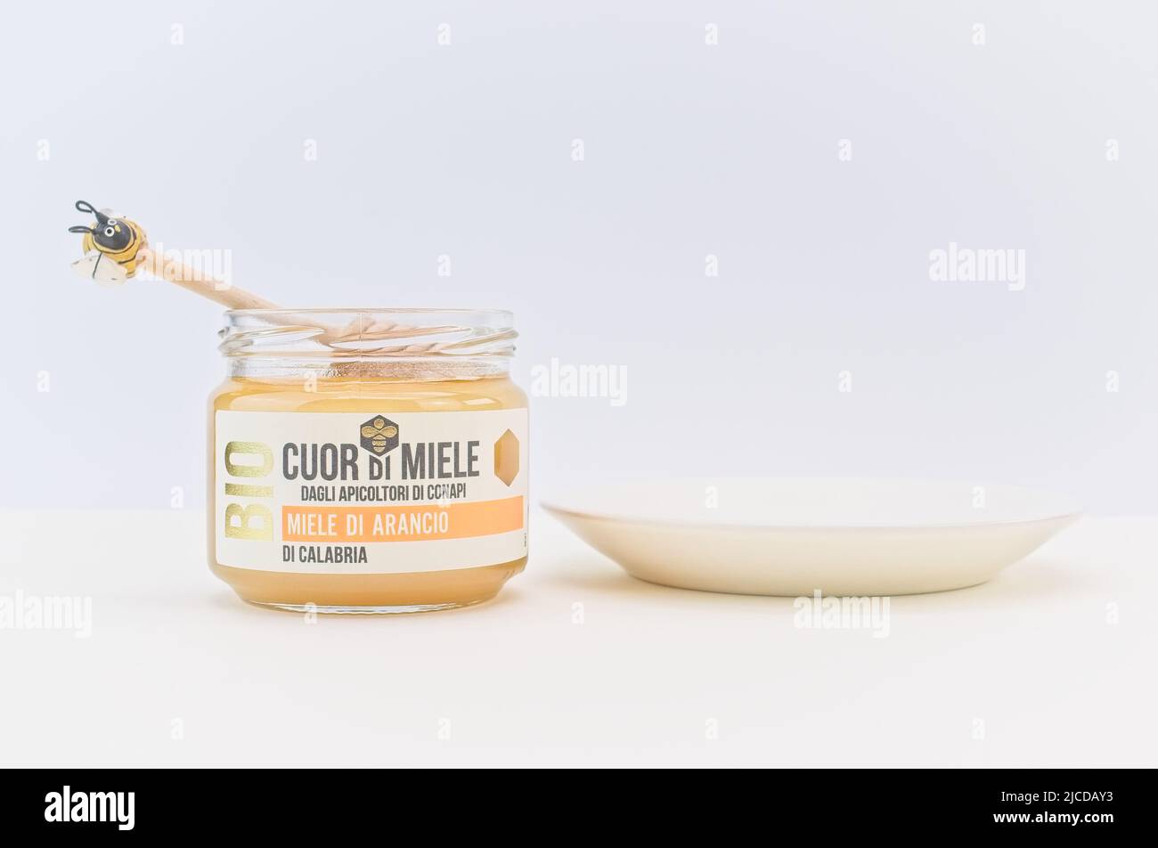 Bio-Bio-Honigglas mit Holzhonigtaube und weißem Dessertteller auf einem hellen Tisch Stockfoto