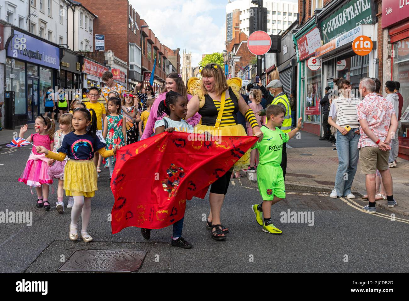 Die Grand Parade am Victoria Day, eine jährliche Veranstaltung in Aldershot, Hampshire, England, Großbritannien. Kinder in Kostümen mit Blumen und Bienen Thema. Stockfoto