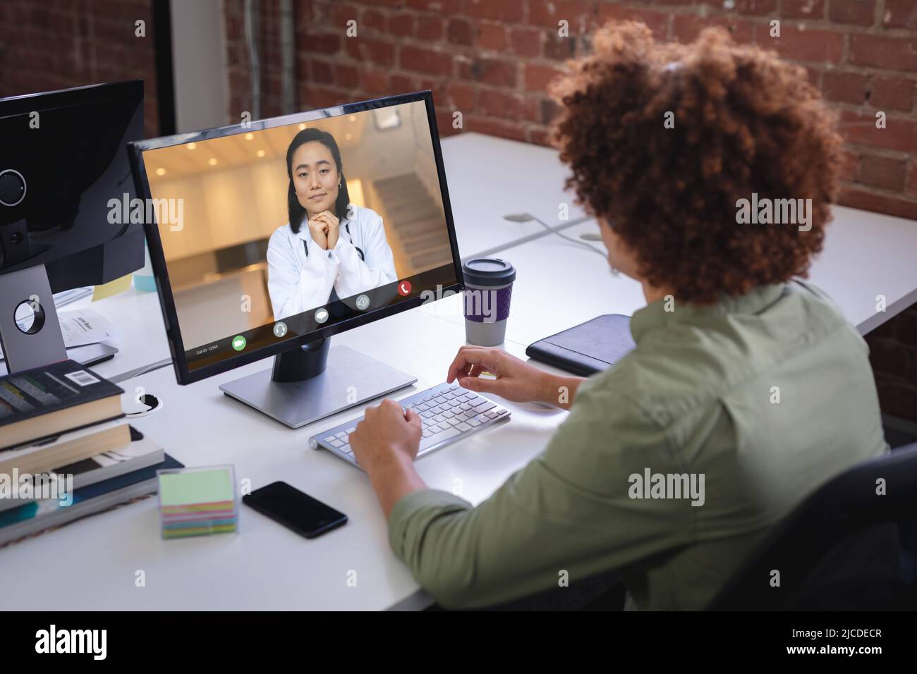 Biracial Geschäftsmann Teilnahme Treffen mit asiatischen Frau über Desktop-pc im Büro Stockfoto
